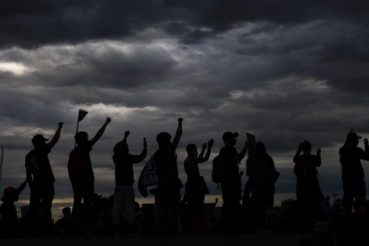 Group of people in silhouette standing up and cheering.