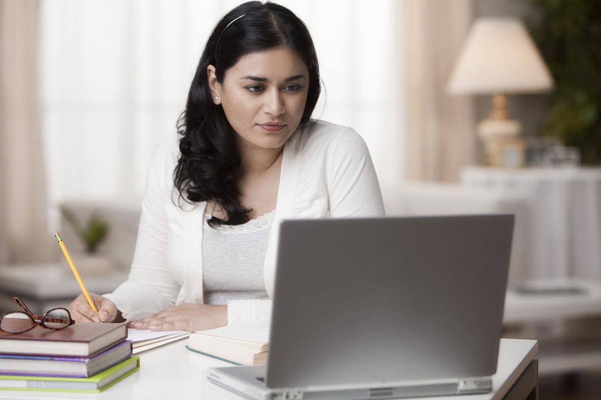 Person looking at a laptop while writing