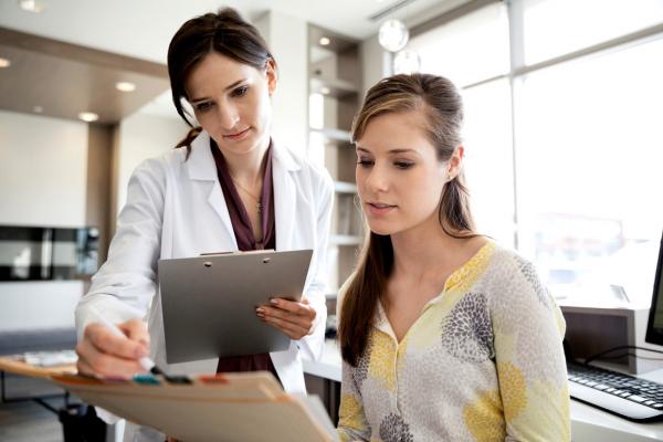 A female doctor and female office staff review CPT codes and medical records.